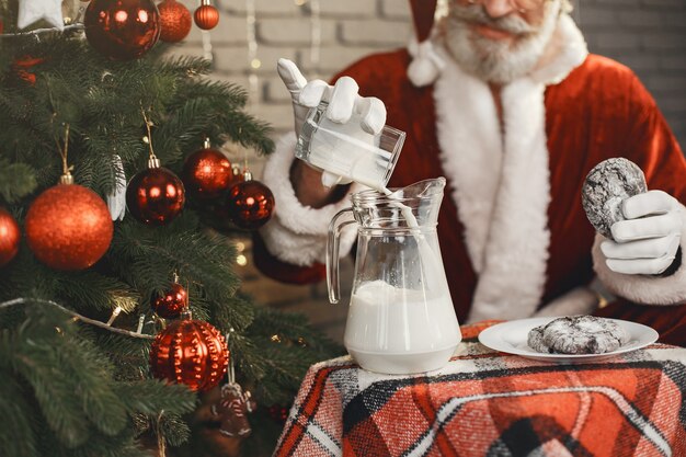 Santa Claus having a rest by the Christmass tree. Home decoration. Gift for Santa.