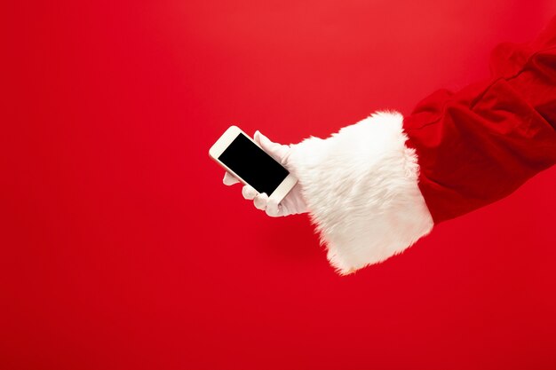 산타 클로스 빨간 스튜디오 배경에 크리스마스 시간에 대 한 준비 휴대 전화를 들고. 계절, 겨울, 휴일, 축하, 선물 개념