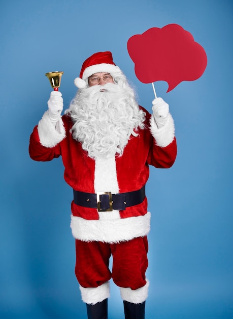 Санта-клаус держит речевой пузырь и колокольчик