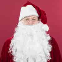 Бесплатное фото Санта-клаус в шляпе, стоя на красном фоне
