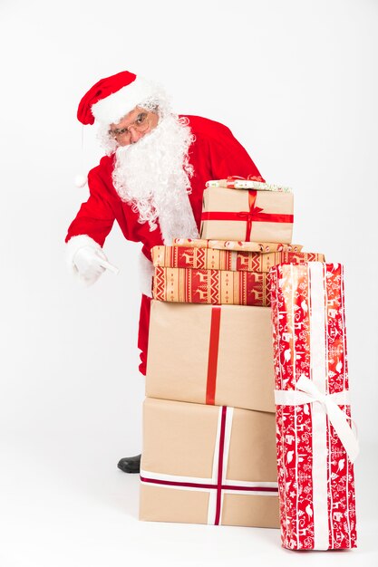 Санта-Клаус, указывая на стек рождественских подарков