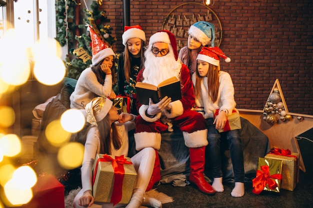 Santa claus reading a book to a group of kids
