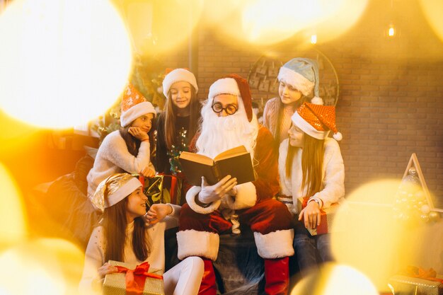 Free photo santa claus reading a book to a group of kids
