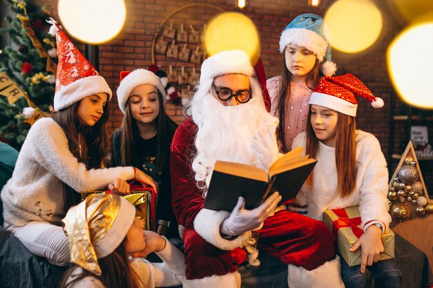 Санта-Клаус читает книгу группе детей