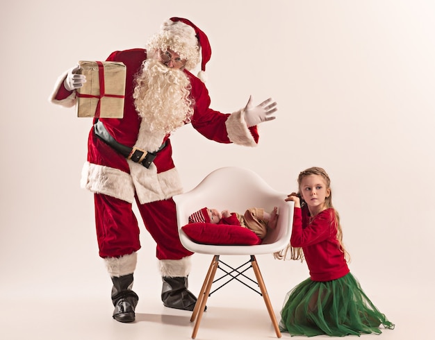 Santa claus in red costume with a little girl and a baby isolated on white