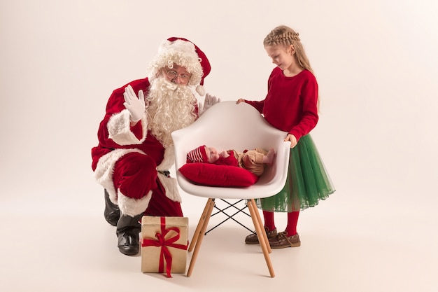 Babbo natale in costume rosso con una bambina e un bambino isolato su bianco