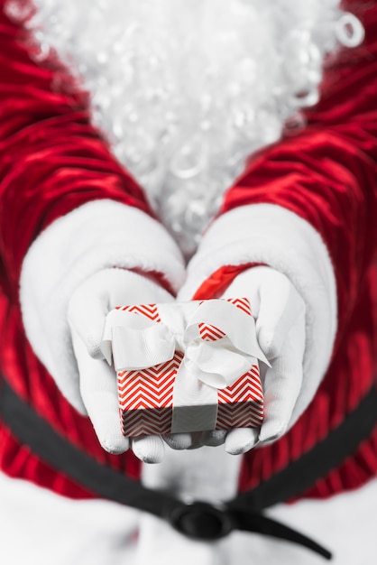 Free photo santa claus in red holding small gift box in hands