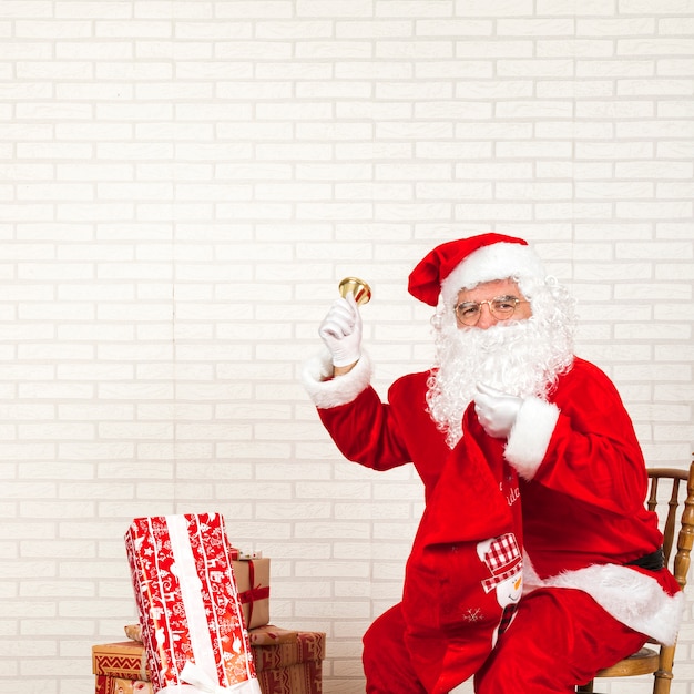 Santa claus ringing bell sitting on chair