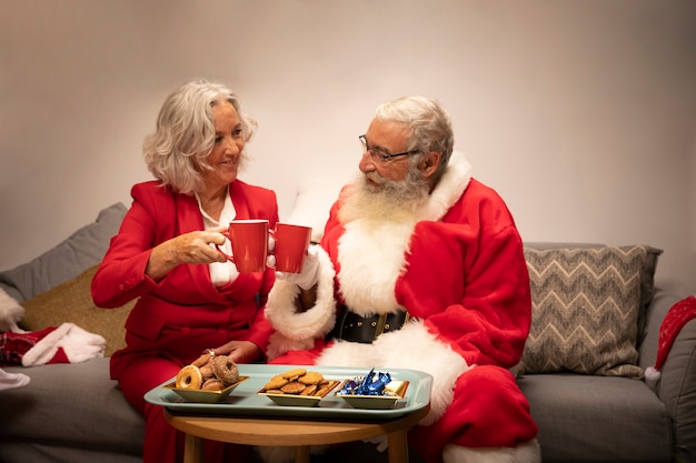 Foto gratuita babbo natale e donna senior che celebra