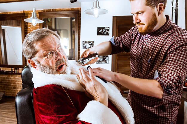 Foto gratuita babbo natale che rade il suo barbiere personale