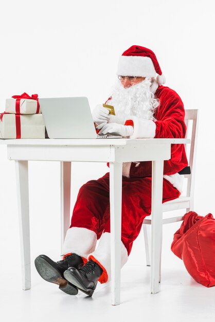 Santa Claus sitting at table with credit card