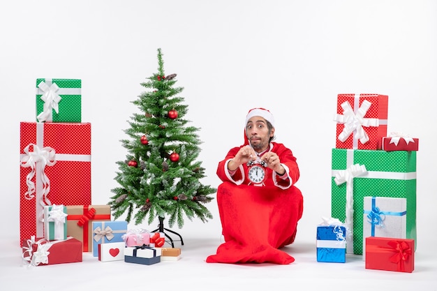 Санта-клаус сидит с подарочными коробками и деревом