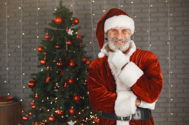 Santa Claus standing by the Christmass tree. Home decoration.