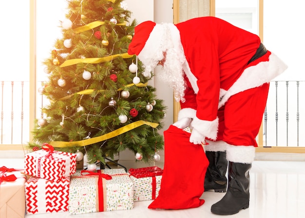 Бесплатное фото Санта-клаус вытаскивает подарки из сумки