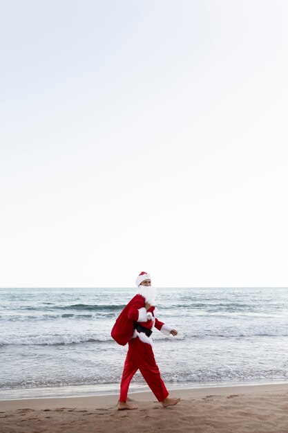 Санта-Клаус ходит по пляжу, вид сбоку