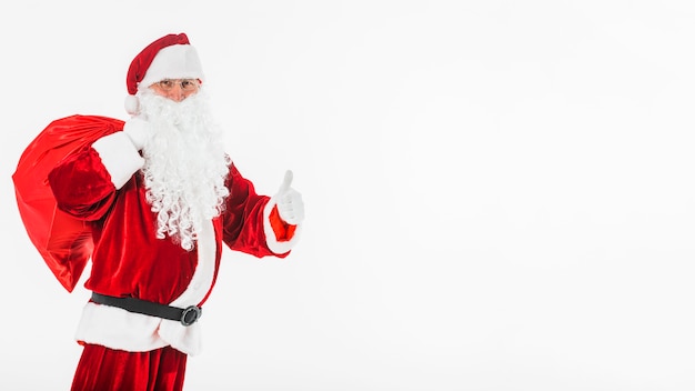 Foto gratuita babbo natale con il grande sacco che mostra pollice sul gesto