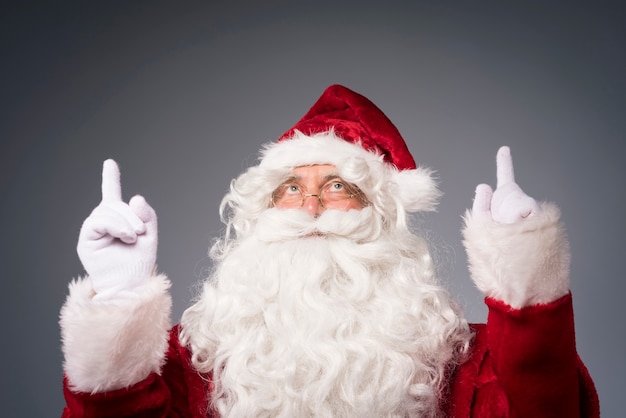 Foto gratuita babbo natale con le mani che mostrano la direzione superiore