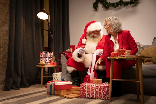 Santa claus wrapping gifts with woman