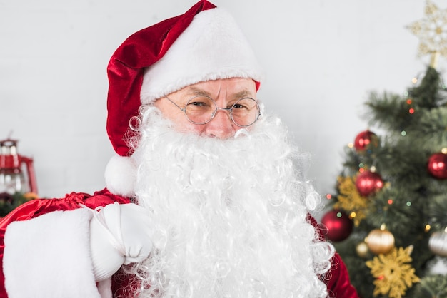 Santa in glasses near Christmas tree