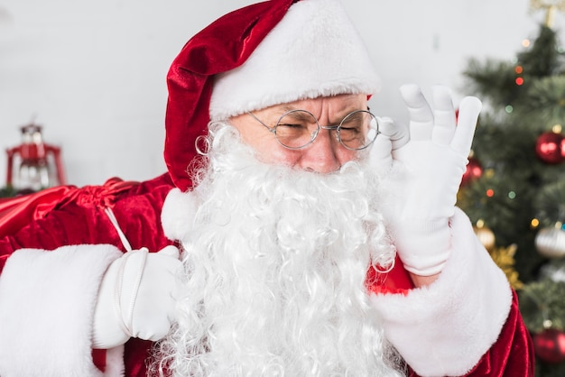 Santa in glasses near decorated Christmas tree