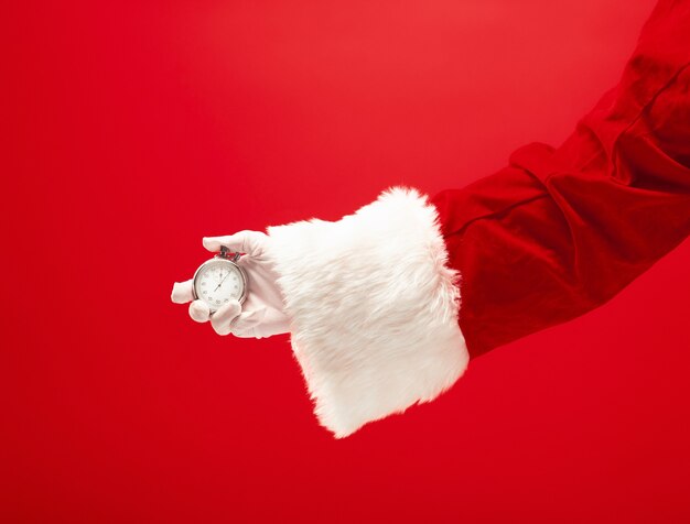 빨간색 배경에 스톱워치를 들고 산타입니다. 계절, 겨울, 휴일, 축하, 선물 개념