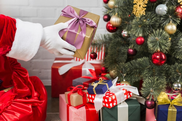 Free photo santa putting gift boxes under christmas tree