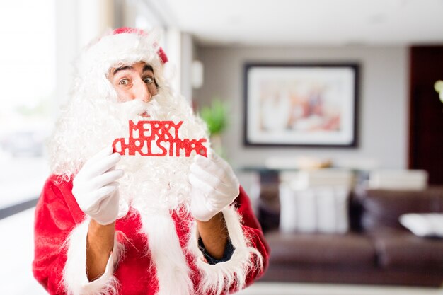 Santa with letters "merry christmas" in a house