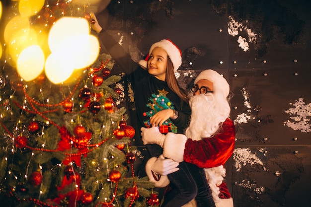 Santa with little girl decorating christmas tree together