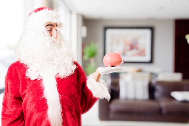 Free photo santa with a peggy bank in a house