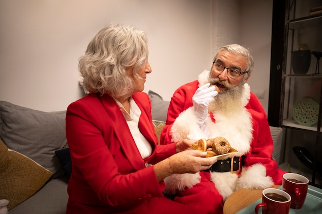 Santa e donna che mangiano i biscotti di natale