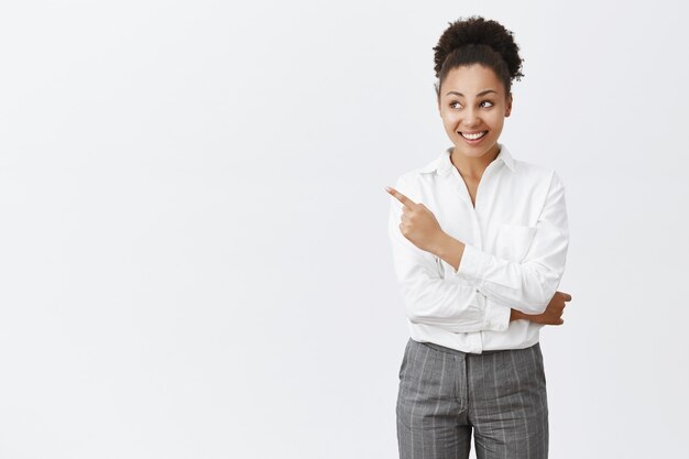 Sassy african american businesswoman showing way, pointing upper left corner