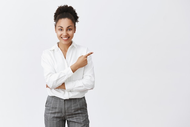 Sassy african american businesswoman showing way, pointing upper right corner