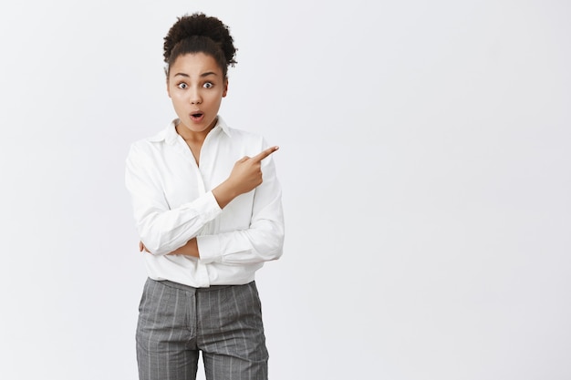 Sassy african american businesswoman showing way, pointing upper right corner