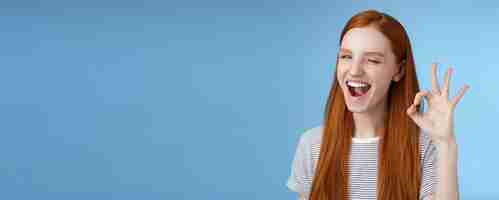 Free photo sassy attractive redhead girl winking mysteriously smiling broadly give approval sign show okay ok