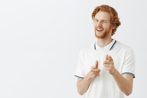 Foto gratuita ragazzo dai capelli rossi barbuto impertinente in posa contro il muro bianco