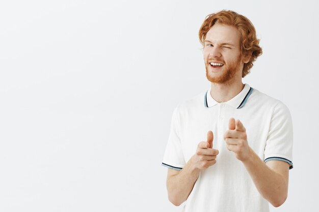 Sassy bearded redhead guy posing against the white wall