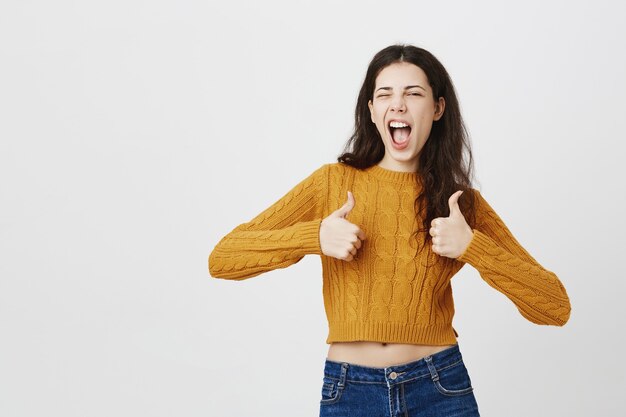 Sassy and excited pretty girl showing thumbs-up