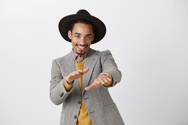 Free photo sassy good-looking african-american man in suit dancing and smiling happy