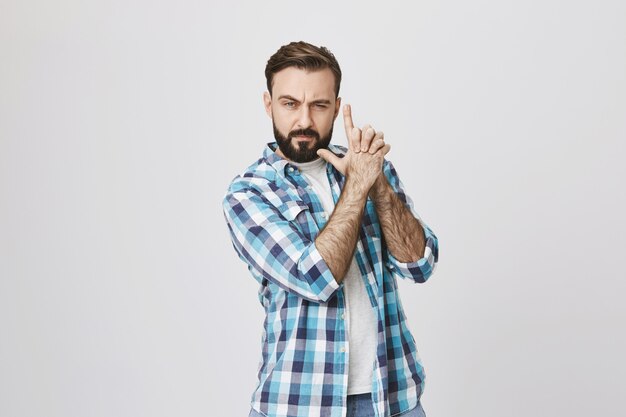 Sassy good-looking bearded man acting like secret agent with gun