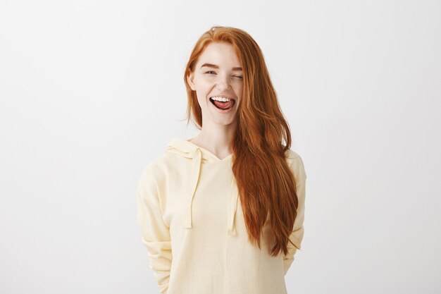 Sassy good-looking redhead girl smiling happy, wink and showing tongue