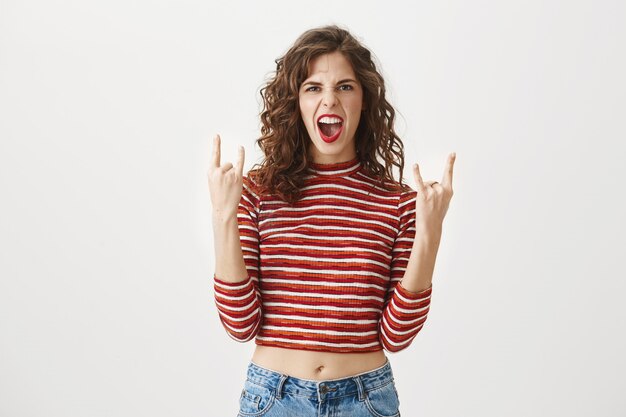 Sassy good-looking woman shouting and showing heavy metal gesture