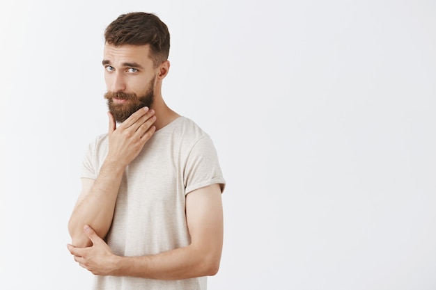 Sassy handsome bearded man posing against the white wall