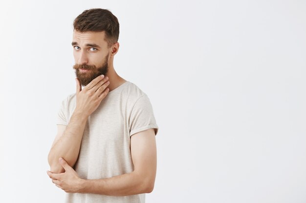 Sassy handsome bearded man posing against the white wall