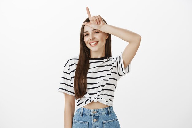 Sassy and pleased girl who won showing loser gesture over forhead, mocking lost team