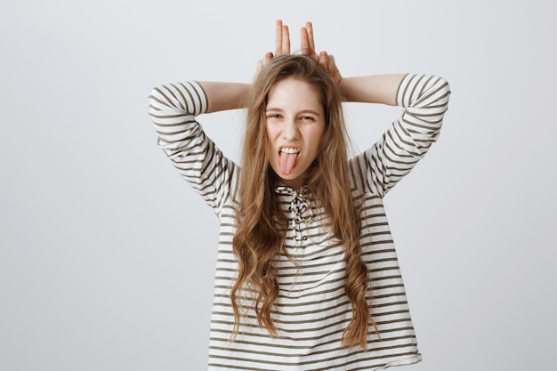 Free photo sassy pretty girl wink and showing bunny ears gesture and tongue