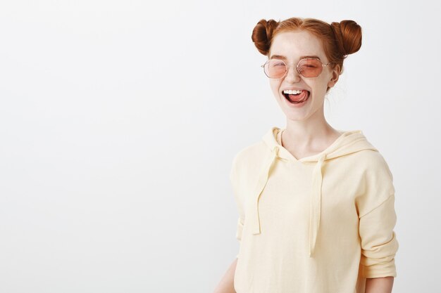 Sassy redhead girl in stylish sunglasses showing tongue