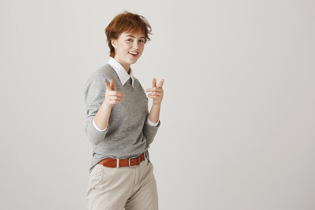 Sassy redhead girl with short haircut posing against the white wall