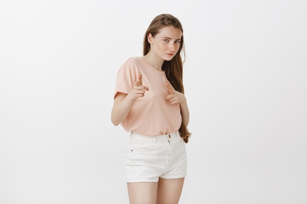Sassy redhead teenage girl posing against the white wall