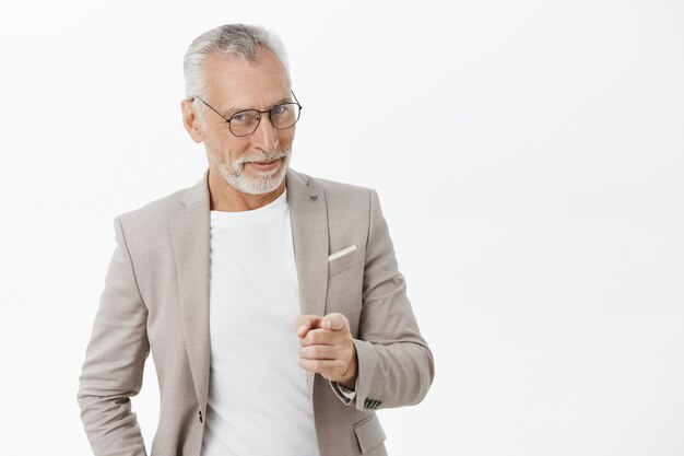 Sassy smiling senior businessman with beard and grey hair pointing