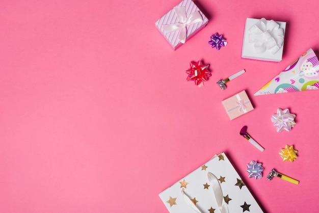 Satin bow; gift boxes; party hat and paper bag on pink background